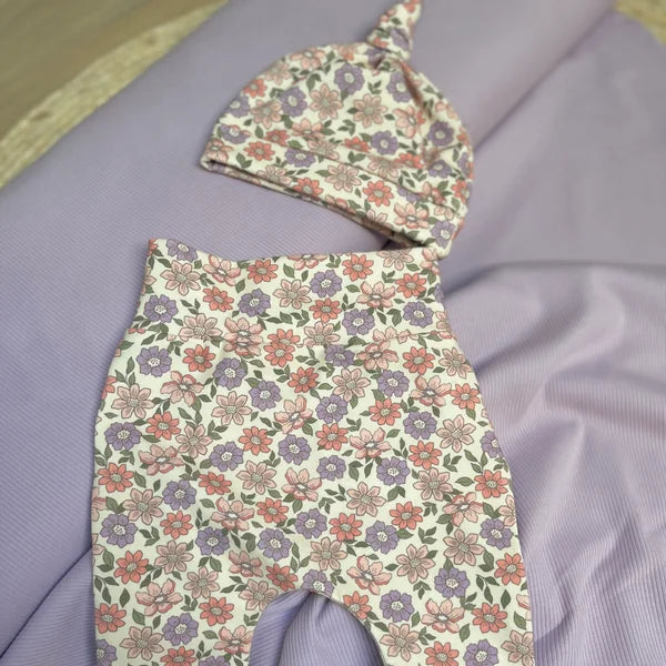 Een lila gebloemd babybroekje en lila gebloemd babymutsje